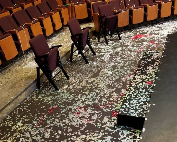 Confetti and streamers cover the floor in front of the stage at The Reif after a live performance or celebration, with rows of auditorium seats visible in the background.