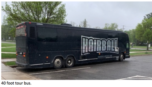 202506-Screen-Shot-2025-06-25-at-12.29.12-PM-600x344 Large black tour bus with the word ‘HAIRBALL’ displayed in bold silver letters is parked along a rainy street lined with green trees. Text at the bottom reads: ‘40 foot tour bus.