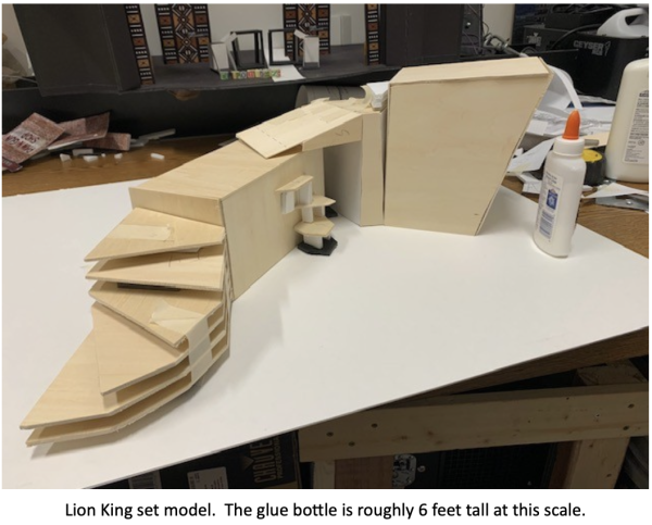 S202511-Screen-Shot-2025-11-07-at-3.42.46-PM-600x483 Wooden scale model for a Lion King stage set displayed on a worktable, featuring layered steps, platforms, and an angular Pride Rock structure beside a bottle of glue used to show scale. Caption at the bottom reads: ‘Lion King set model. The glue bottle is roughly 6 feet tall at this scale.